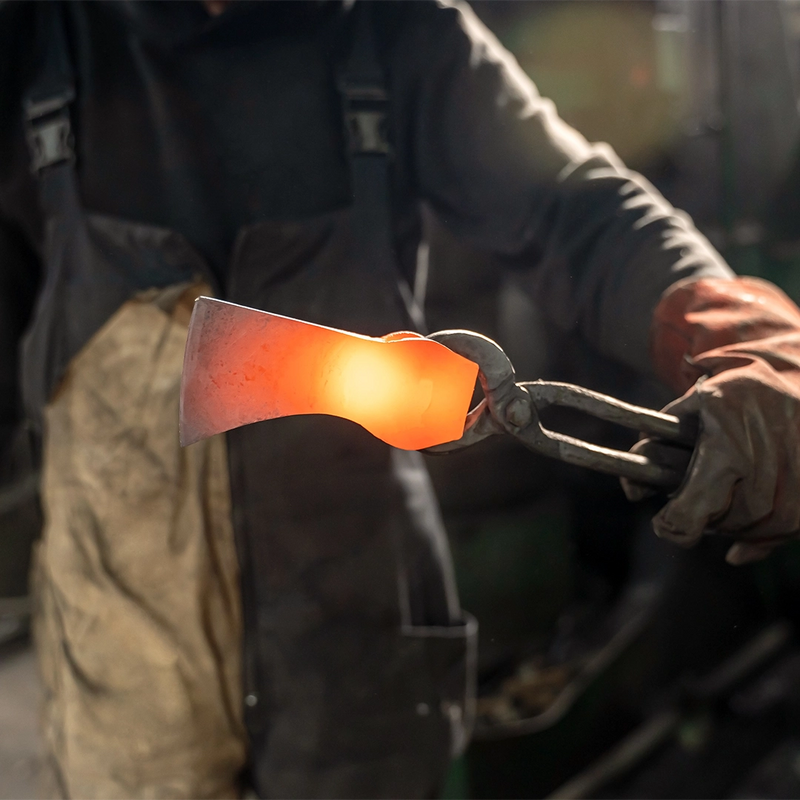 Forging a glowing axe head, held in tongs