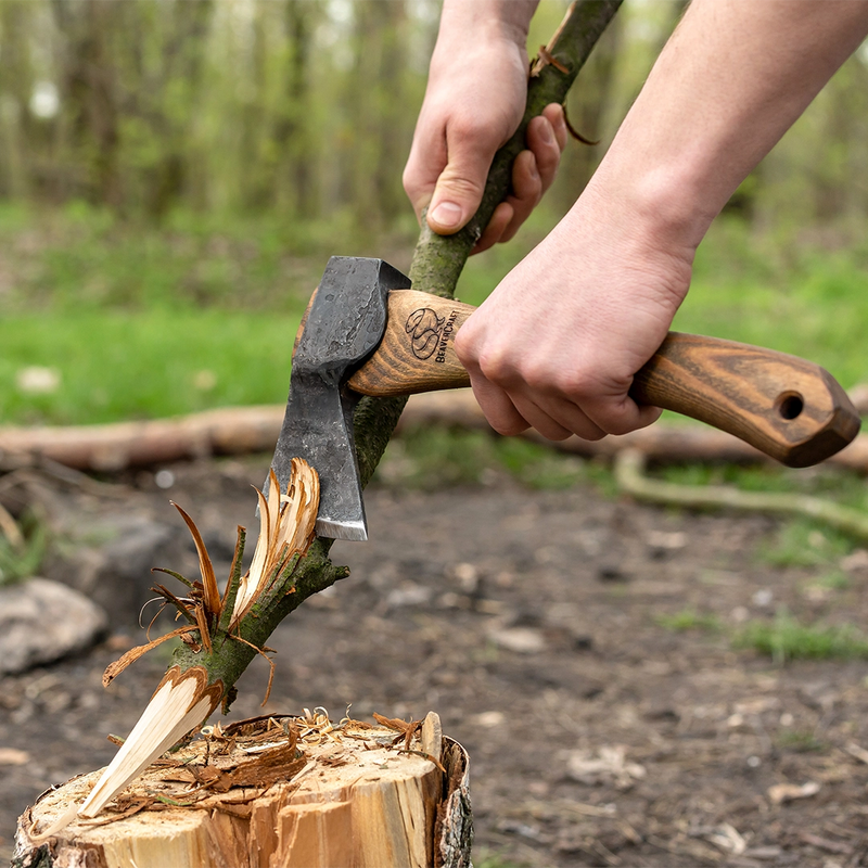 Shaping the end of a stick with the AX1 on a stump in the forest